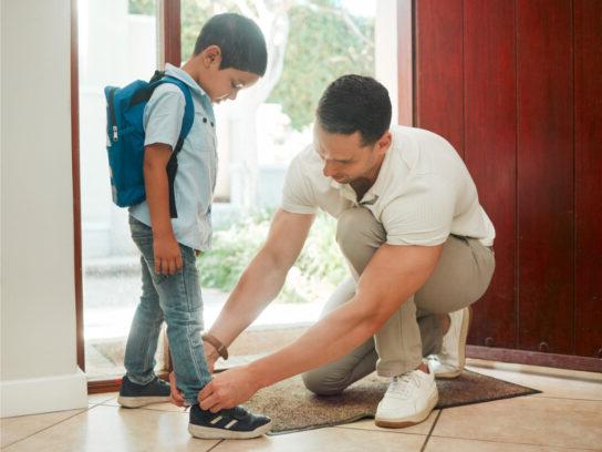 photo of father and son adjusting shoes at home getting ready for school